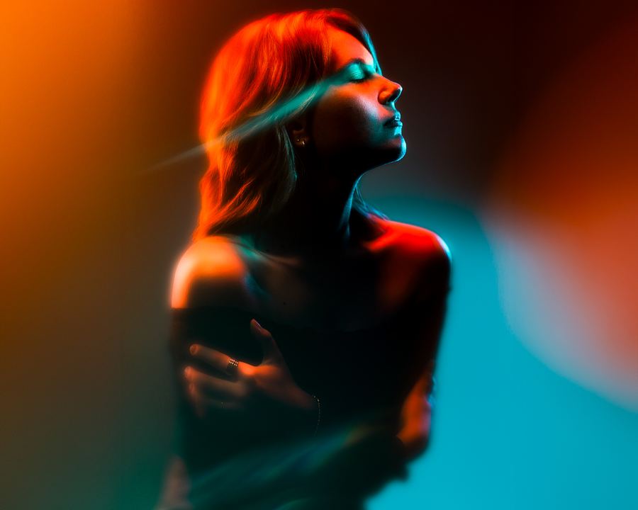 Sunblind: Head tilted back in orange light against teal, a beam crossing the eyes
