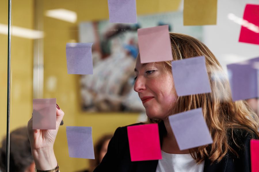 Arranging lilac and pink sticky notes on a glass wall, shot through the glass