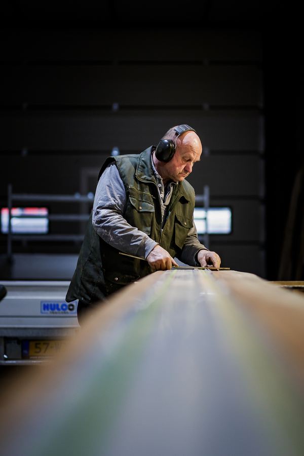 A print operator in ear defenders checking a sheet coming off the press