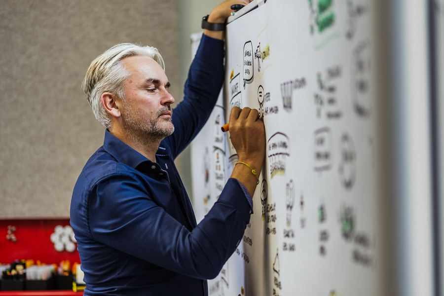 Drawing a process map on a whiteboard, marker in hand