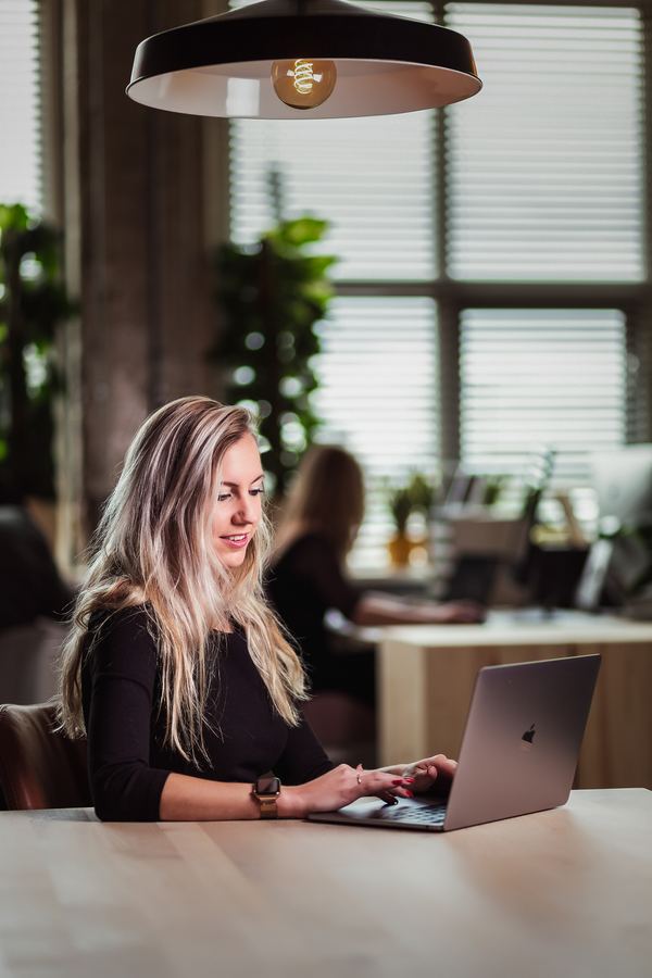Working on a laptop at a long wooden table under a pendant lamp
