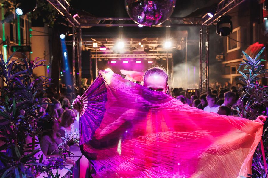 A performer spreading pink silk fan-veils in front of the stage