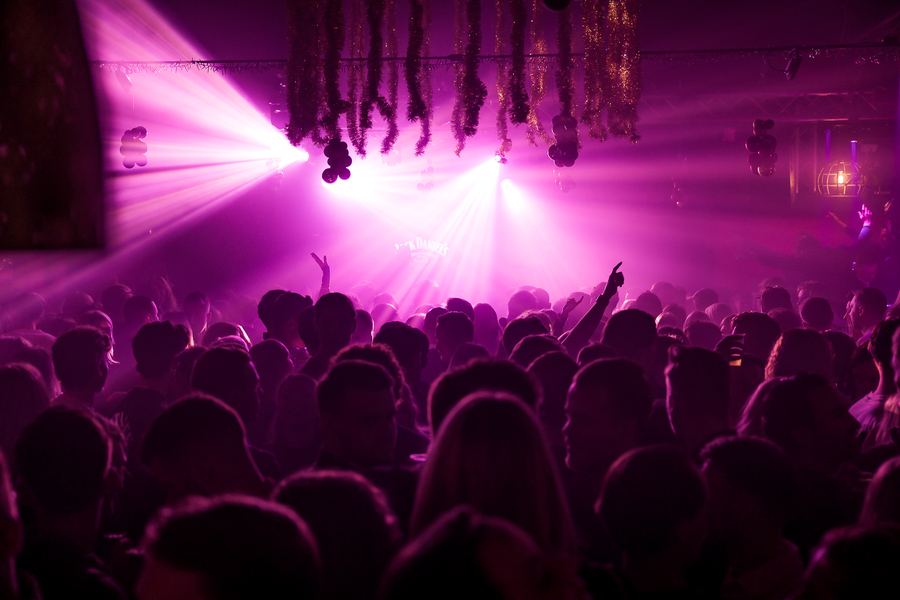 Hands up in a wash of magenta spotlights