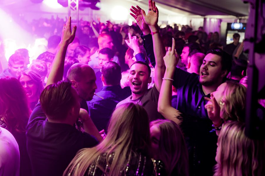 Arms in the air on a purple-lit dance floor