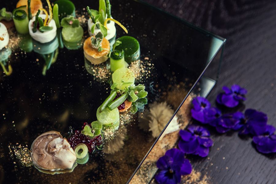 Amuse-bouches on a glass plate beside purple violas