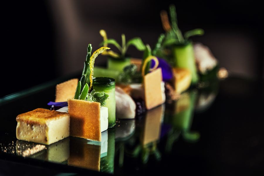 Small bites lined up on black glass, each with its reflection