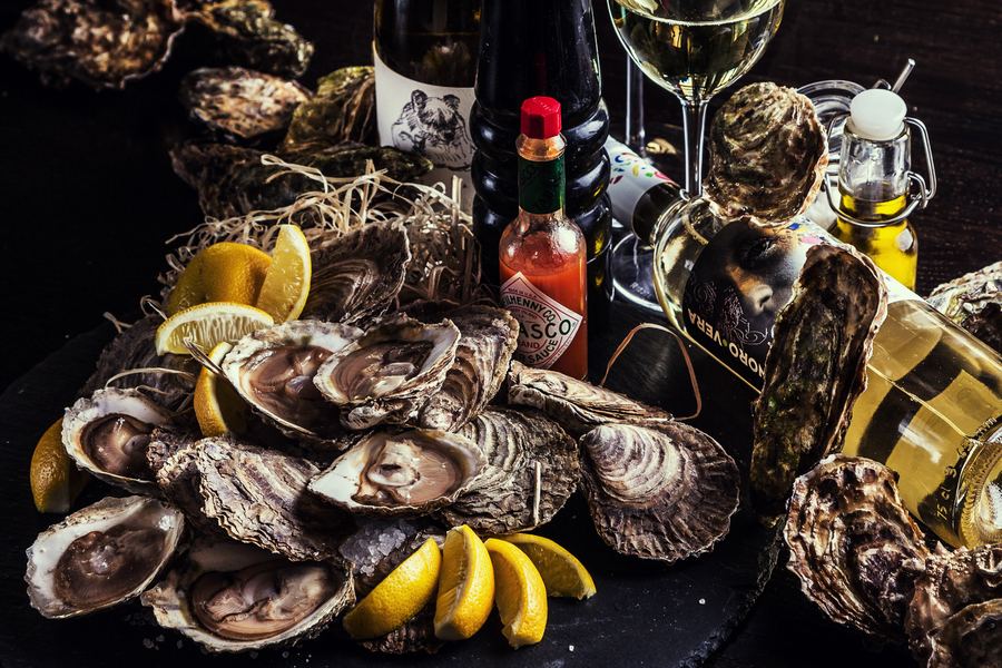 A pile of oysters with lemon wedges, Tabasco and white wine
