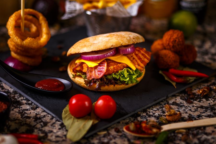 Bacon cheeseburger with a stack of onion rings and bitterballen