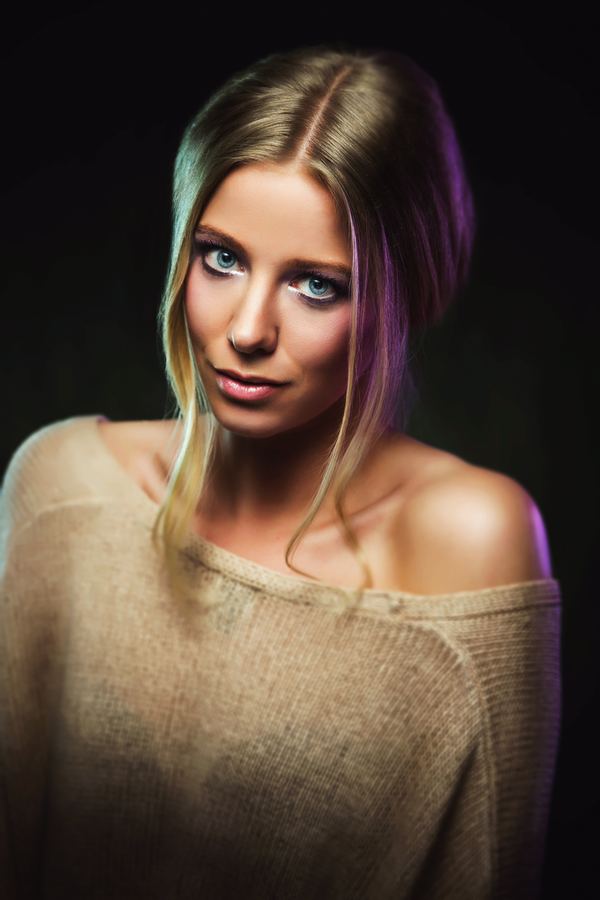 An off-shoulder knit and loose blonde strands, edged with violet light