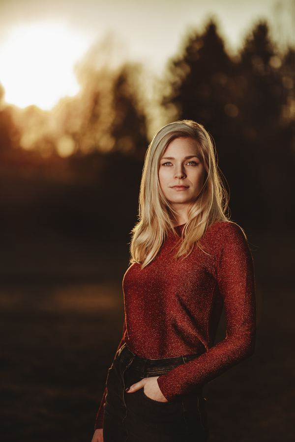 A red glitter sweater in the last light, pines out of focus behind