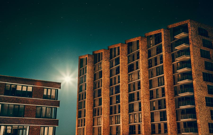 Brick apartment towers under a starry sky, a streetlight flaring between them