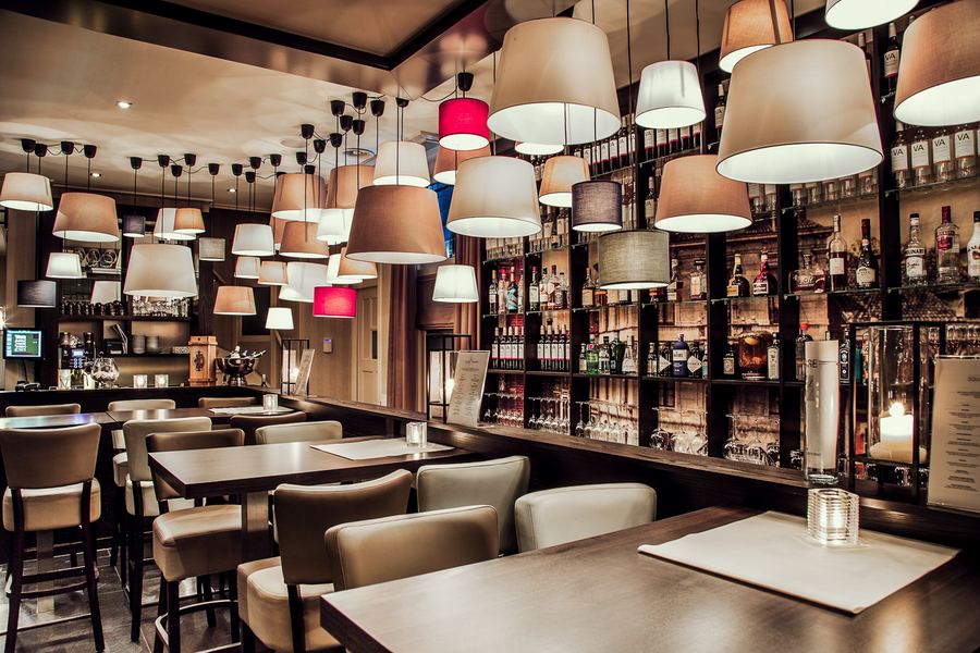 A brasserie under dozens of mismatched lampshades