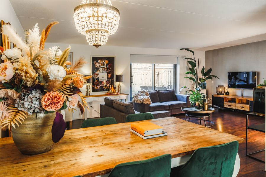A living room with a chandelier, dried flowers on an oak table