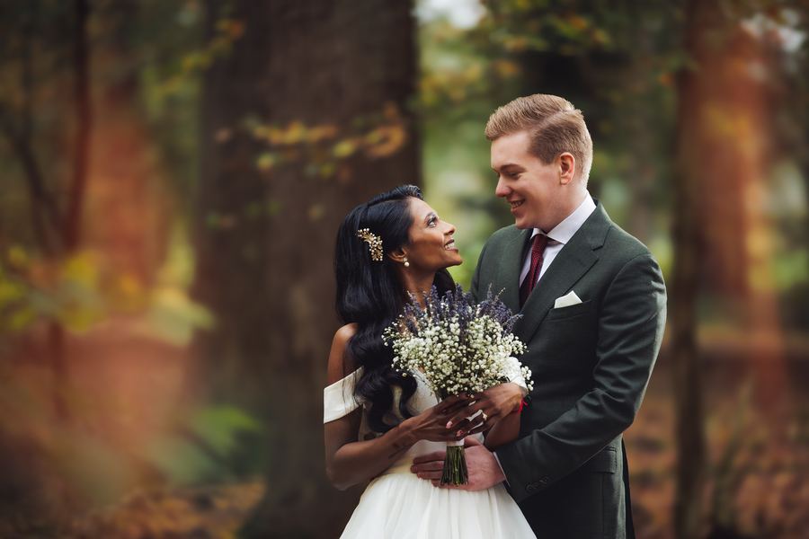 She looks up at him, a baby’s-breath bouquet between them, in autumn woods