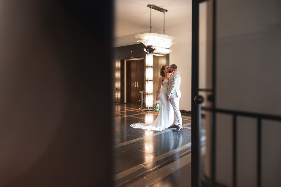 A kiss under a chandelier, seen through a half-open door