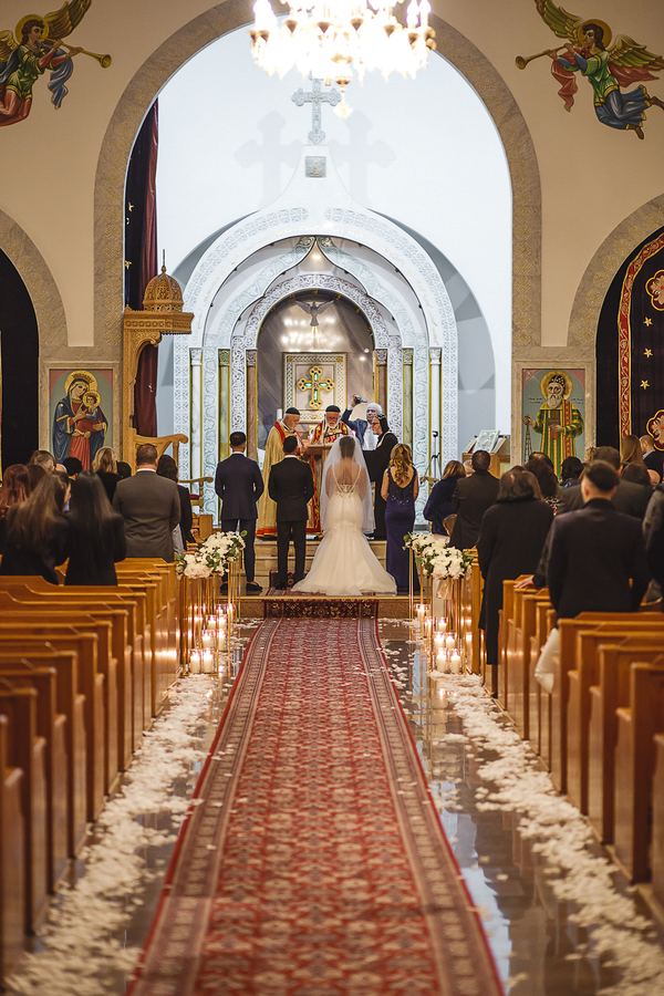 The ceremony seen from the back of the aisle, petals along the carpet